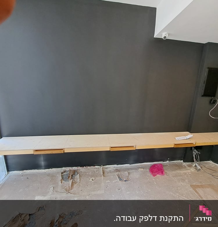 מדף עץ מותקן על קיר אפור בחדר